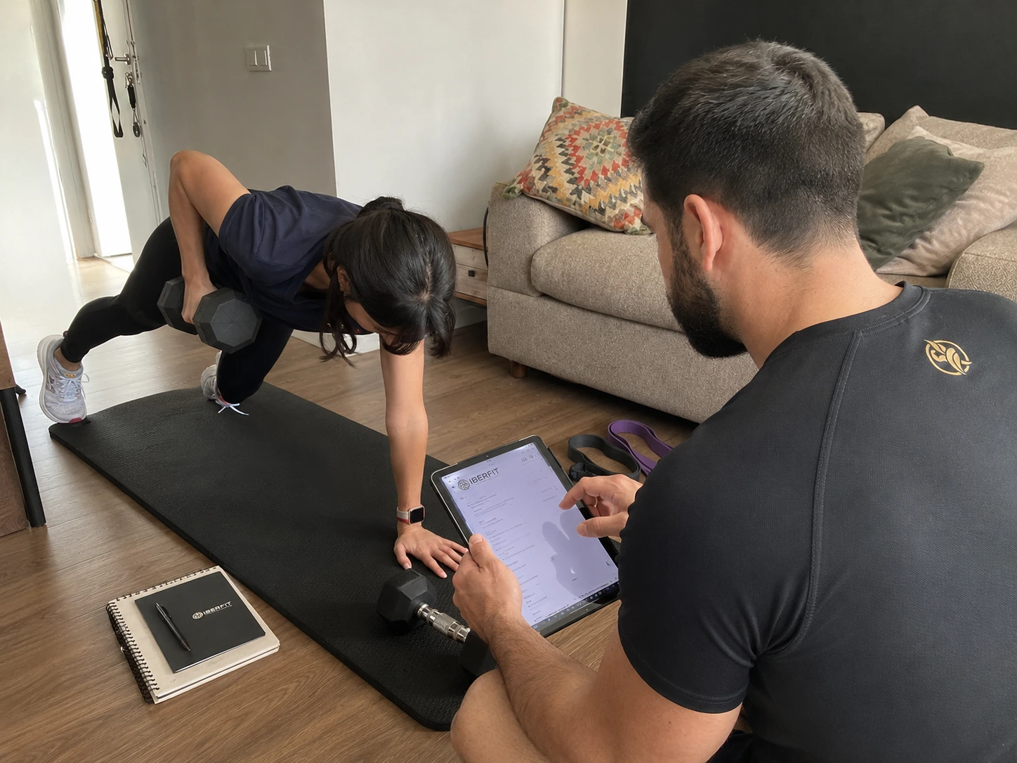 Entrenador IBERFIT revisando en una tablet la ejecución durante una sesión híbrida.